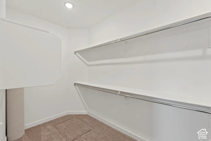 Recessed lighting illuminates a neutral-toned carpeted floor and white walls