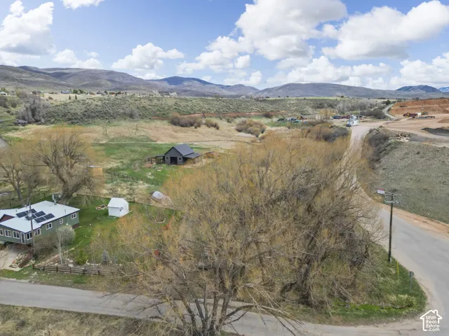 Ranch-style residence featuring a sloped roof with solar panels, a detached outbuilding, and a separate barn structure, all set against a backdrop of distant hills
