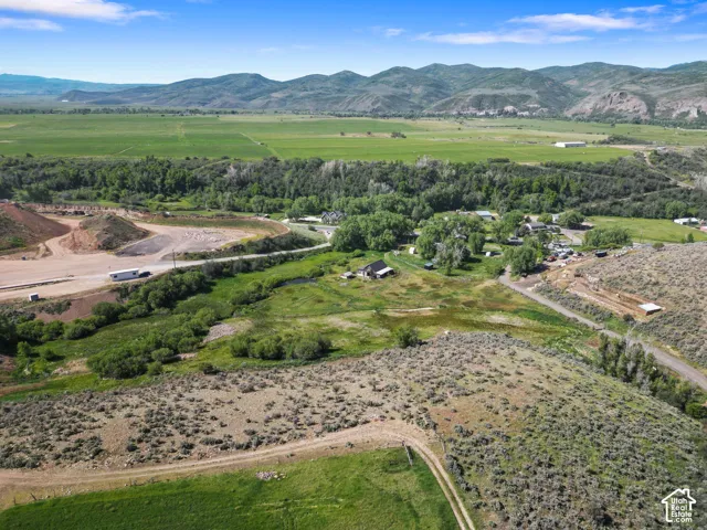 Expansive land parcel featuring mountainous terrain, mature trees, and a distant body of water