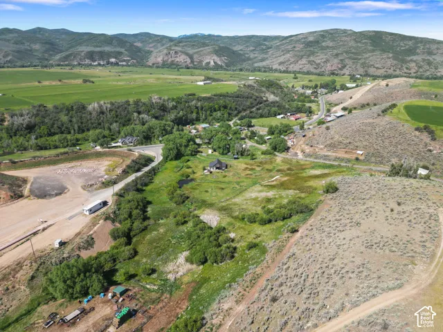 Expansive rural landscape featuring rolling hills, abundant green spaces, and a winding road