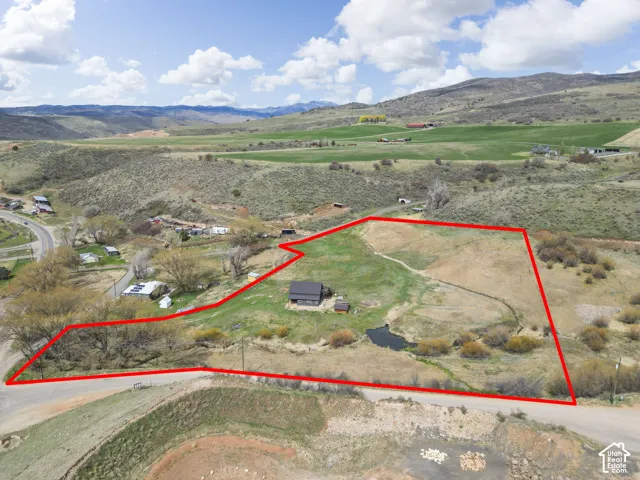 Expansive land parcel featuring a central structure, a pond, and varying terrain