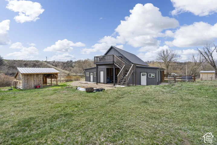 Modern barn-style structure with a dark exterior, a metal roof, and a second-story deck