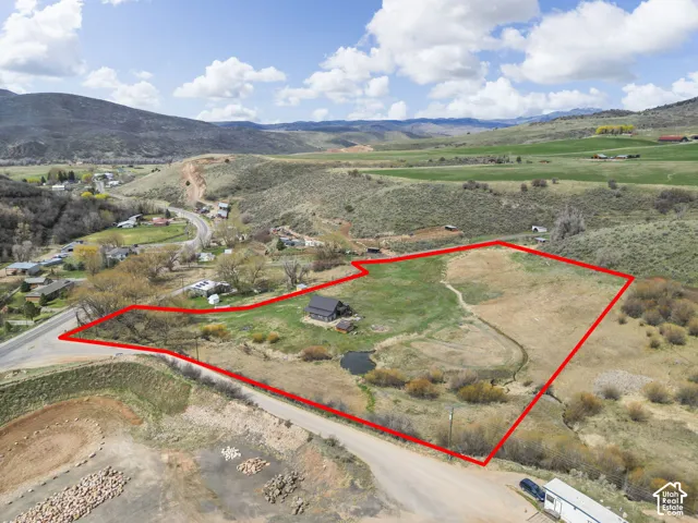 Expansive land parcel with a single-family structure, a distinct pond feature, and diverse terrain