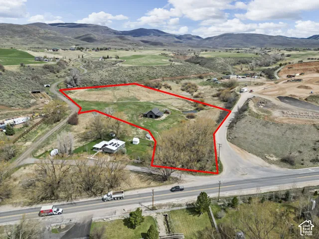 Expansive land parcel with surrounding mountains, visible road frontage, and a distant structure