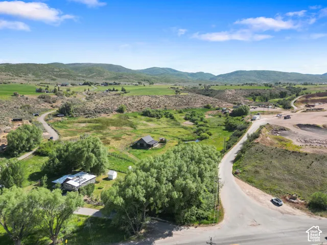 Expansive property with a single-story residence and a detached shed, surrounded by mature trees and natural landscaping
