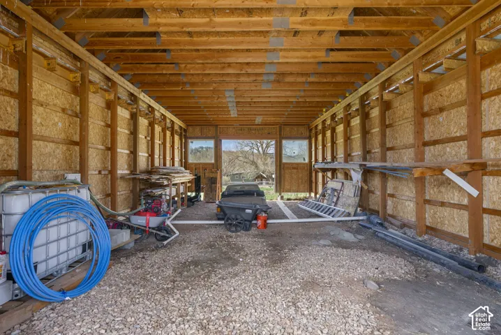Exposed wood beam ceiling, raw wood walls, stone floor, and a large opening