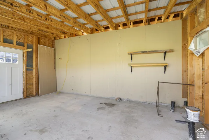 Exposed wood framing, metal ceiling panels, concrete flooring, and a white paneled door with window inserts