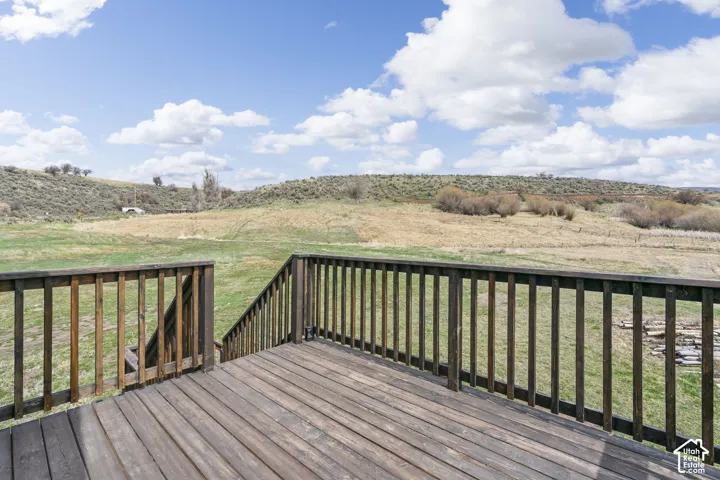 Expansive wood deck with stairs and wood railing overlooking a natural landscape