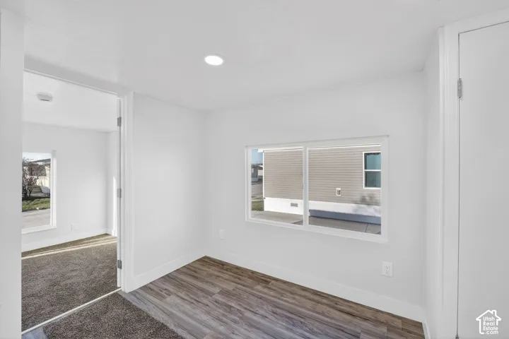 Recessed ceiling lighting, wood-finish flooring, white walls, and a window with a white frame