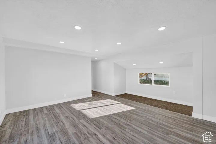 Recessed lighting with a white ceiling, wood-finish flooring, and a window providing natural illumination