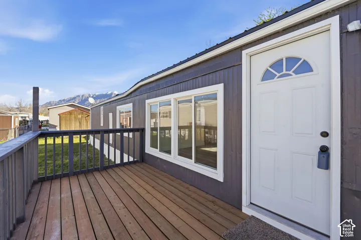 Exterior featuring a wood deck, white framed windows, and a white entry door with an arched transom