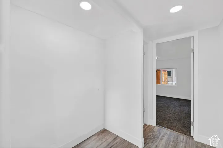 Recessed ceiling lighting, wood-finish flooring, white walls, and white trim