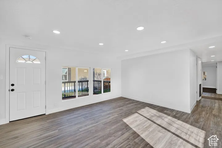 Entry door with an arched transom, wood-finish flooring, recessed lighting, and multiple windows
