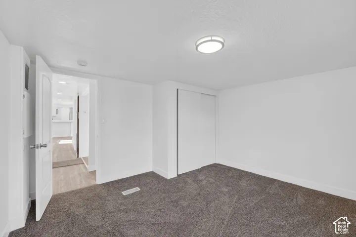 Neutral white walls, gray carpet flooring, white trim, and a flush-mount ceiling light