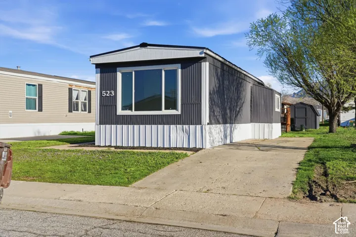 Exterior featuring a gray and white siding facade, white window trim, and a concrete driveway