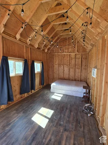 Exposed wood beam ceiling with string lighting, wood-finish flooring, and two windows