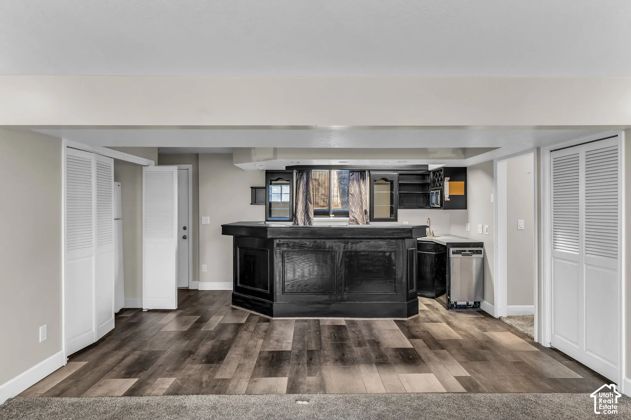 Wet bar with dark cabinetry, stainless steel dishwasher, and a sink