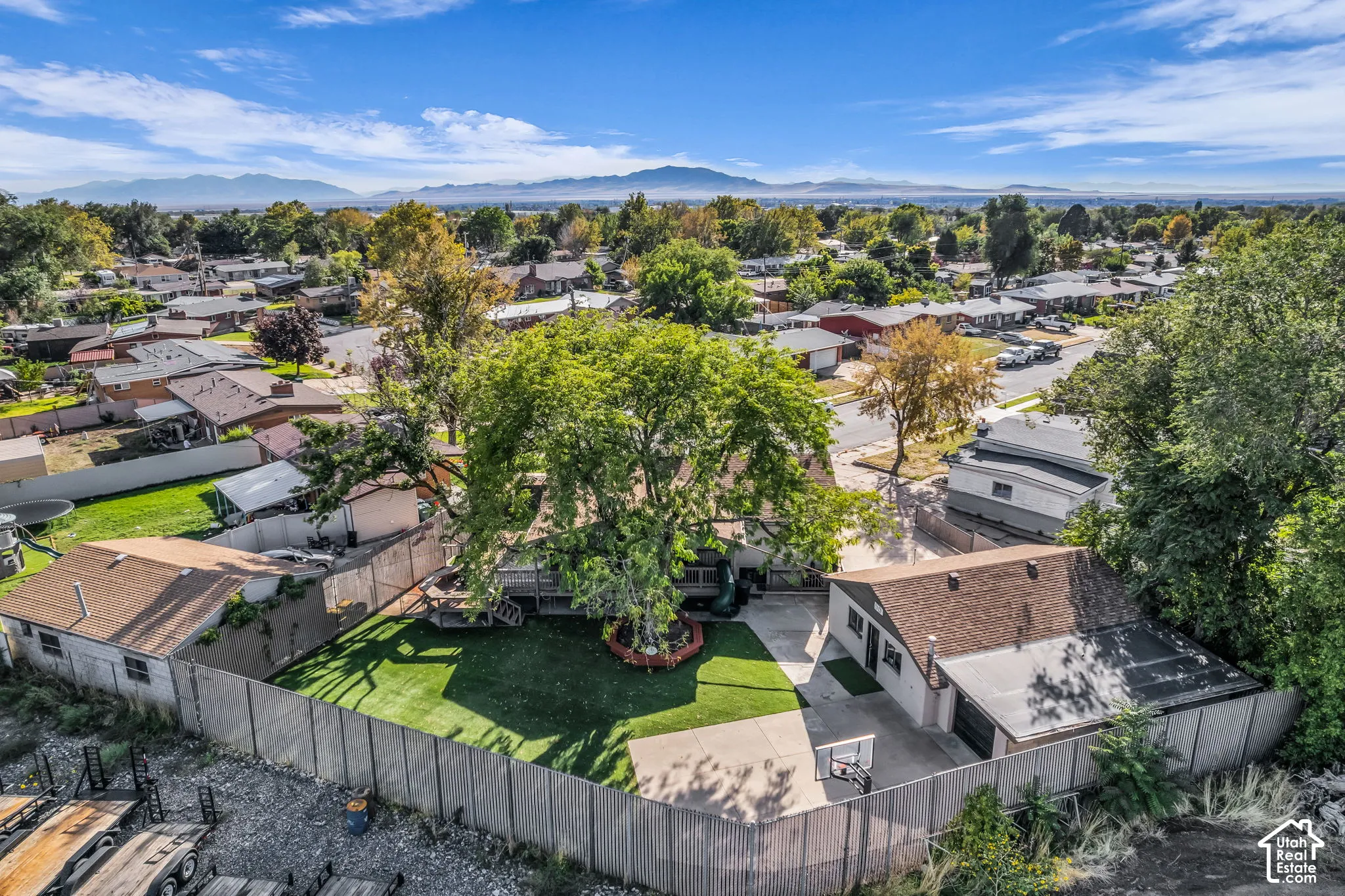 Expansive backyard featuring a manicured lawn, established trees, and a concrete patio