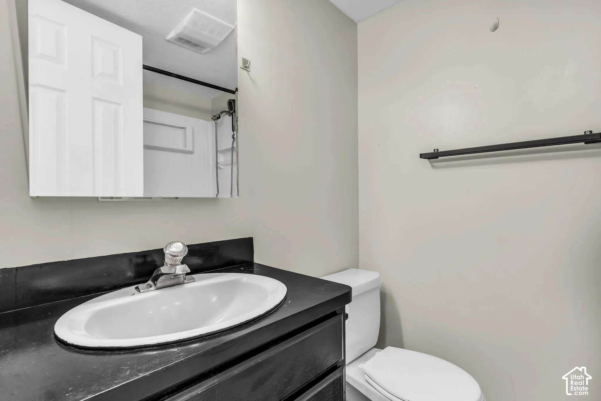 Vanity with an integrated sink, wall-mounted mirror, and black towel bar