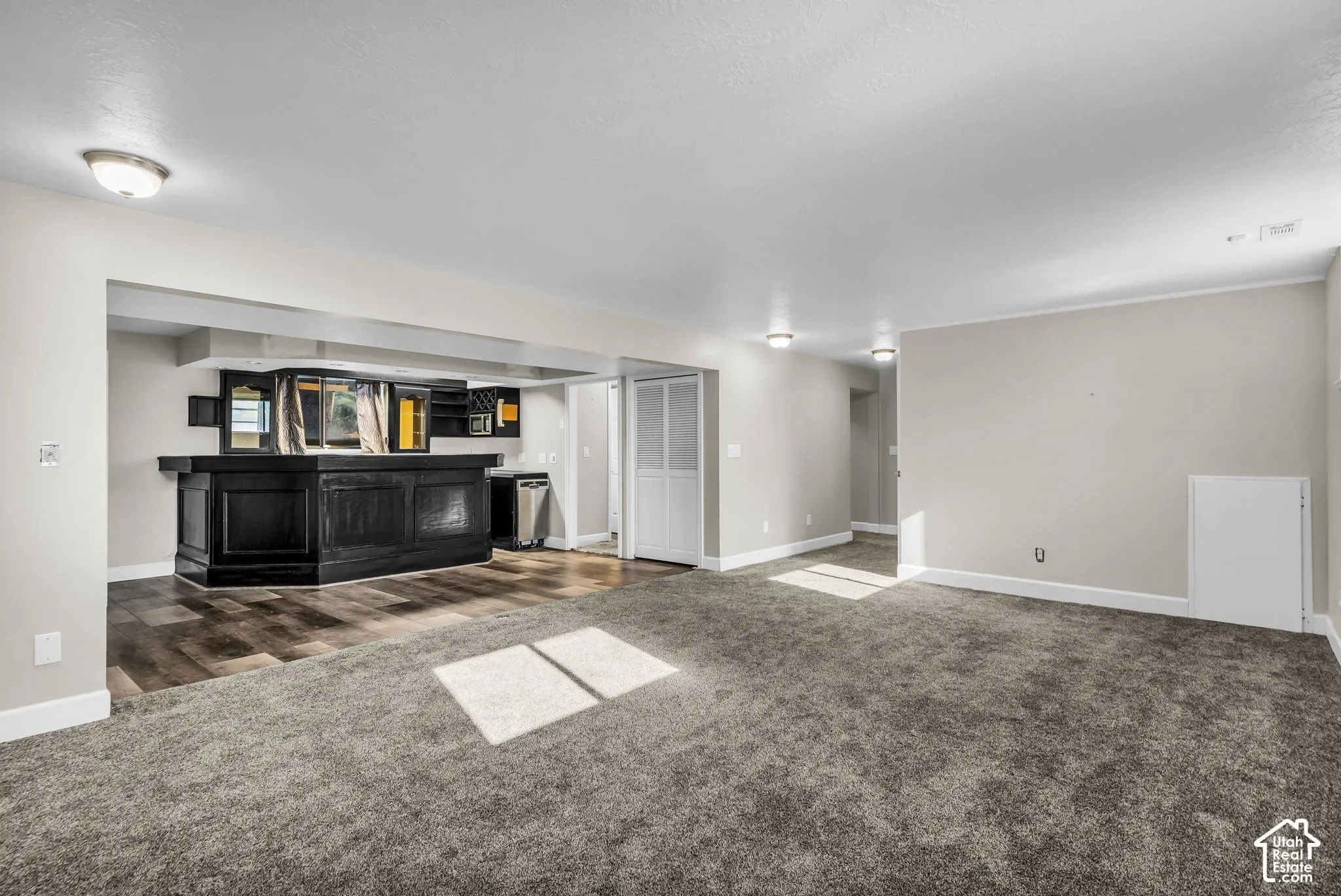Spacious interior with gray carpeting, white baseboards, and neutral wall tones