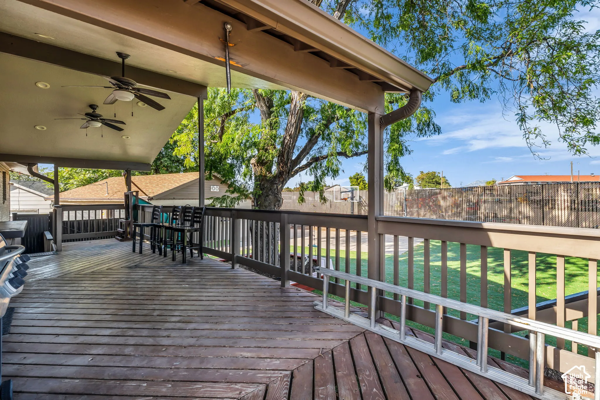 Expansive wood deck with a covered portion, featuring recessed lighting and ceiling fans