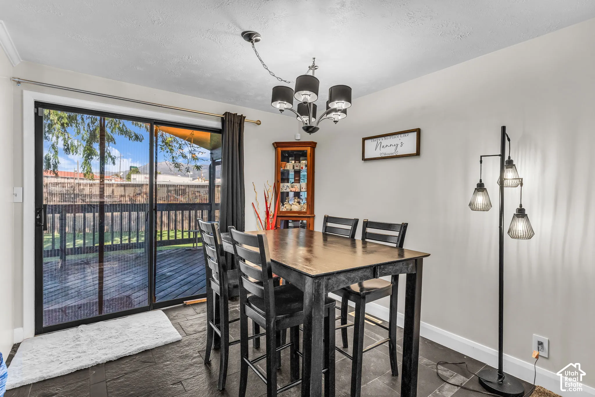 Sliding glass door, deck access, dark slate tile flooring, recessed lighting, and a multi-arm chandelier
