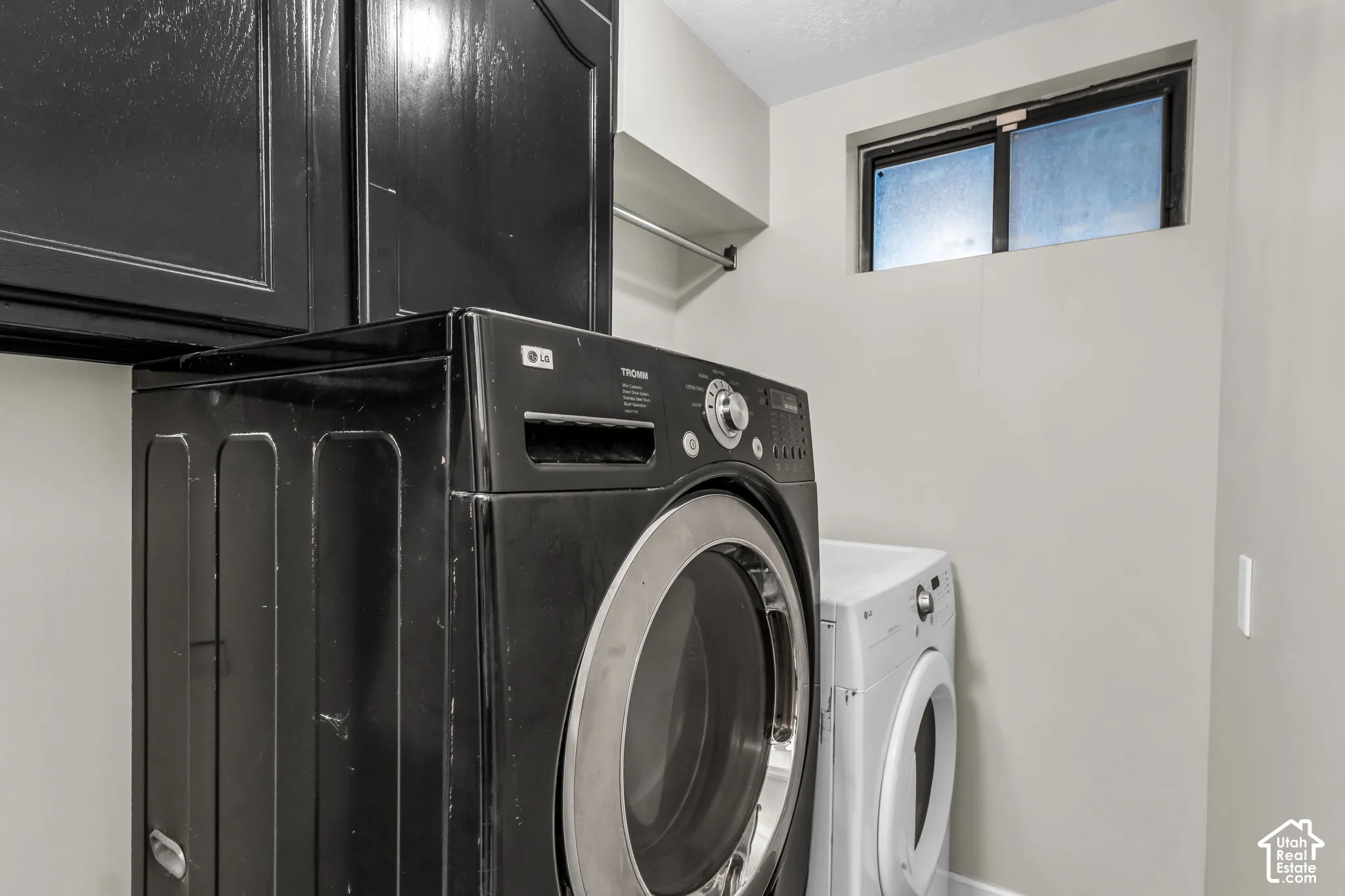 Integrated laundry area with built-in cabinetry and an elevated window