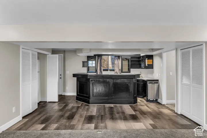 Wet bar with dark cabinetry, stainless steel dishwasher, and a sink