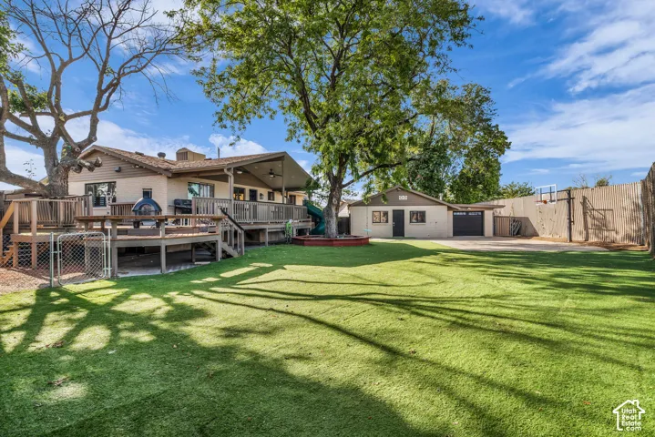 Extensive artificial turf lawn, multi-level wood deck, covered patio, attached garage, and a separate detached garage structure