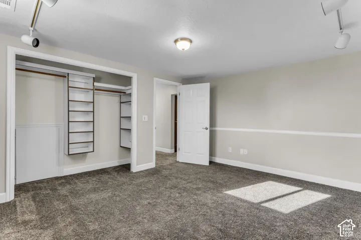Plush gray carpeting, neutral wall palette with chair rail molding, and integrated closet shelving