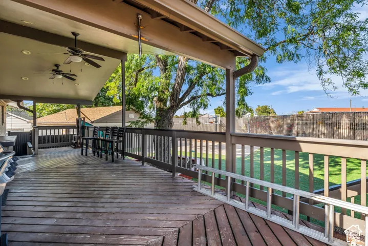 Expansive wood deck with a covered portion, featuring recessed lighting and ceiling fans