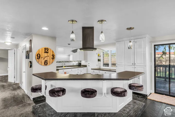 Kitchen featuring a central island with bar seating, white cabinetry, dark countertops, and a sliding glass door