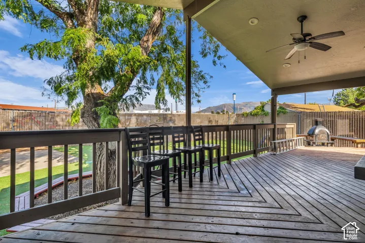 Expansive outdoor deck featuring wood-finish flooring, a covered patio, and a ceiling fan