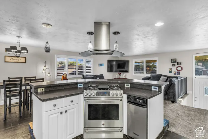 Stainless steel range with overhead hood, dark countertops with white cabinetry, and wood-finish flooring