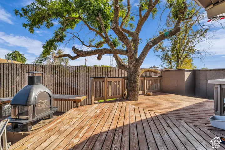 Expansive wood deck with a mature shade tree, a decorative metal outdoor fireplace, and integrated wood benches