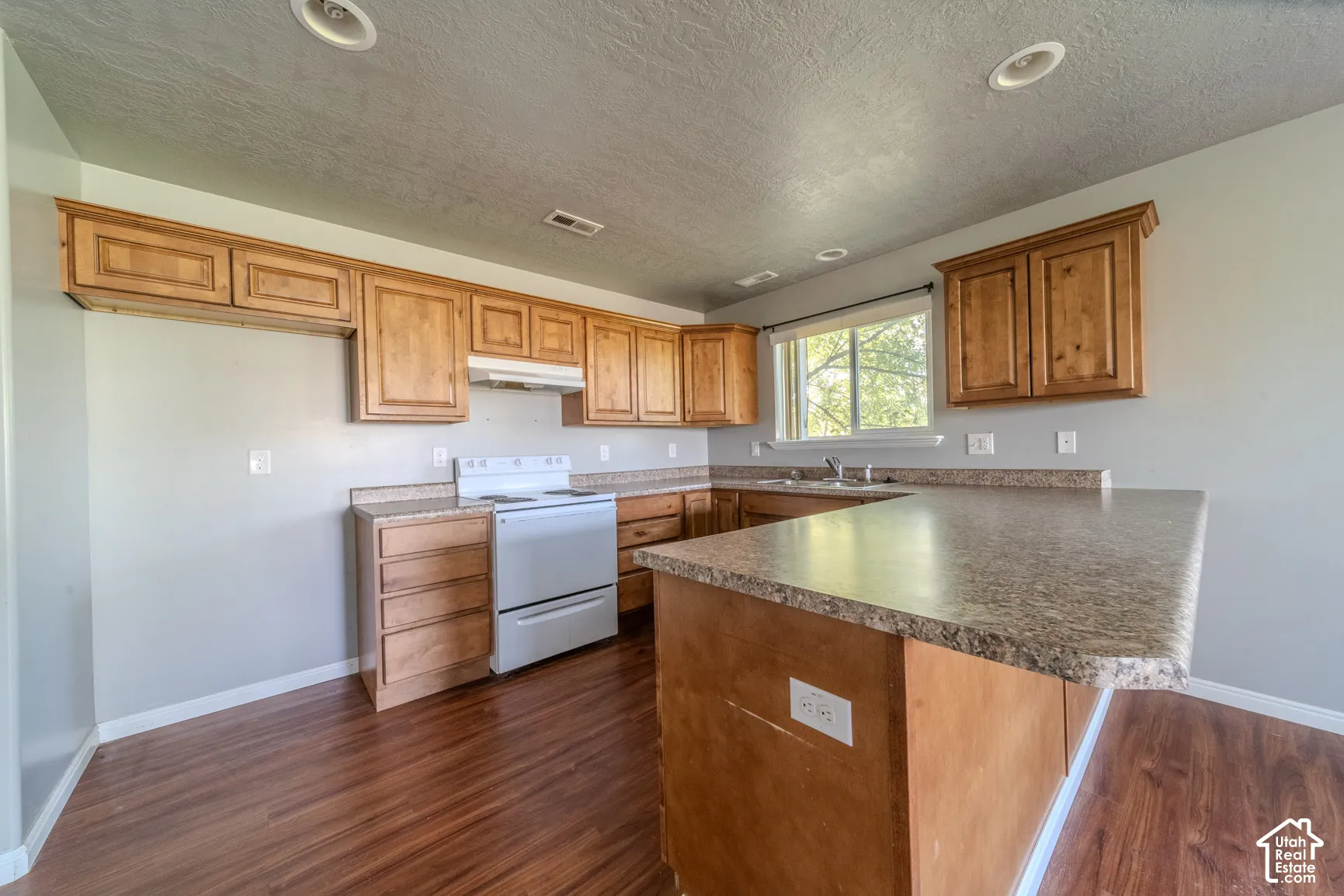 Kitchen featuring wood-finish flooring, wood cabinetry, stone-look countertops, and recessed lighting