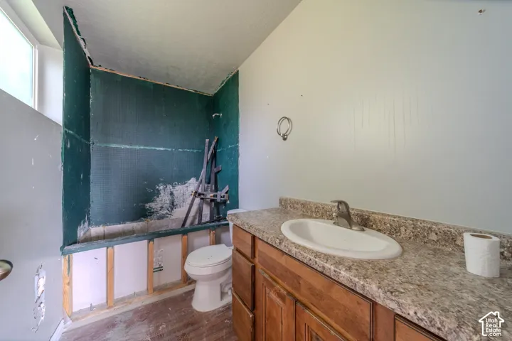 Built-in vanity with wood-finish cabinetry, a single basin sink, and a speckled countertop