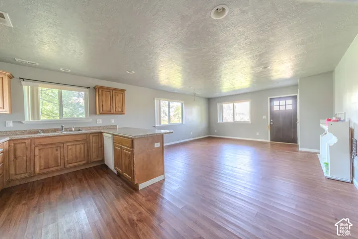 Open-concept living space featuring wood-finish flooring, recessed lighting, a kitchen island with seating, a stainless steel sink, and wood cabinetry