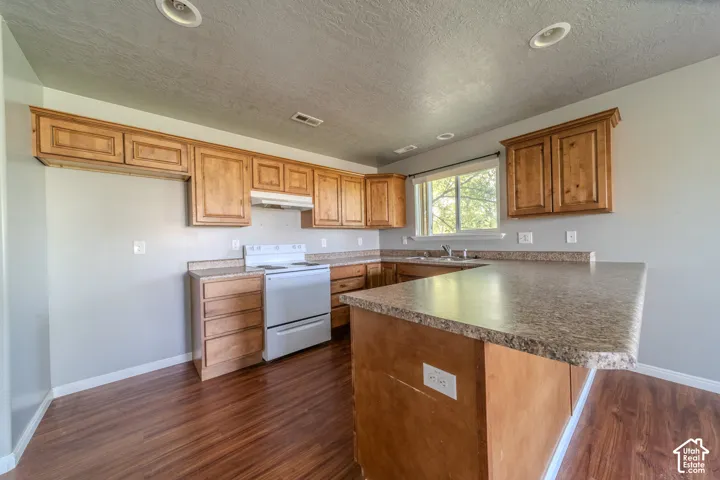 Kitchen featuring wood-finish flooring, wood cabinetry, stone-look countertops, and recessed lighting