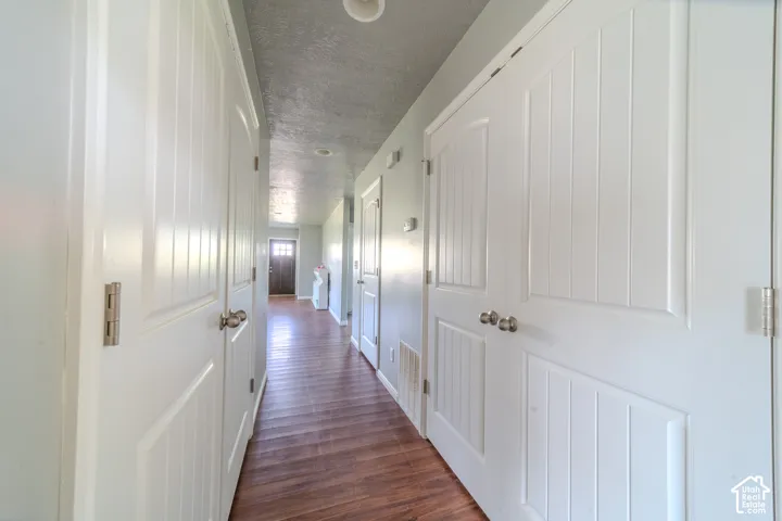 Hallway with wood-finish flooring, white panel doors, and recessed lighting
