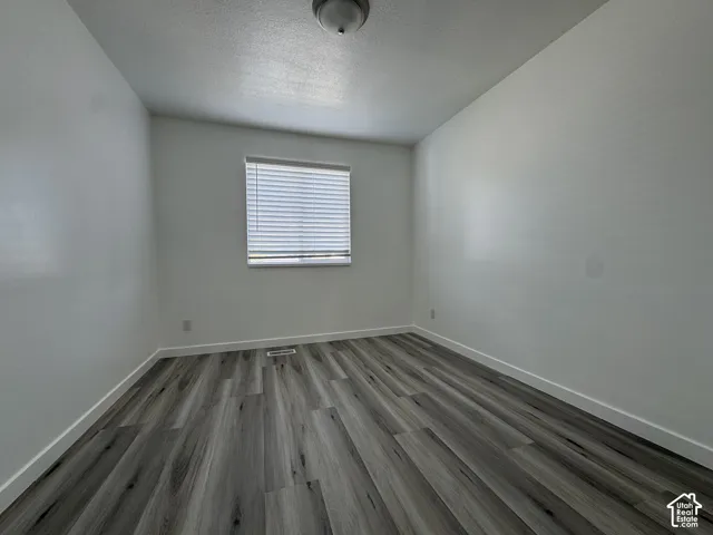 Wood-finish flooring with white baseboards and window blinds