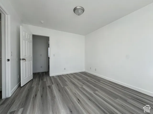 Wood-finish flooring, white walls, and a flush mount ceiling light fixture