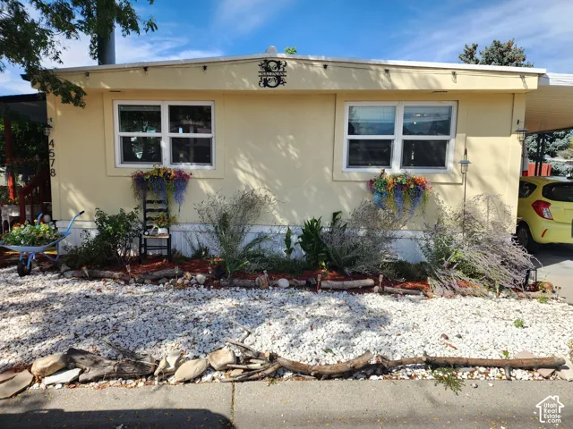 Exterior featuring light-colored siding, white window frames, and a gravel front yard
