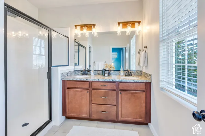 Bathroom featuring a dual vanity with a speckled countertop, integrated sinks, and wood-finish cabinetry