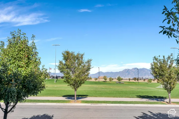 Expansive green space featuring a manicured lawn, established trees, and mountain backdrop