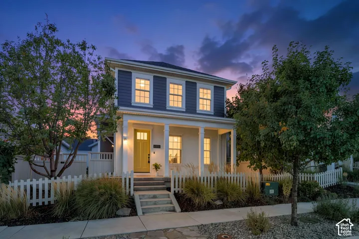 Two-story residence featuring siding and shutters, a covered front porch with white columns, and a bright yellow front door with glass lites