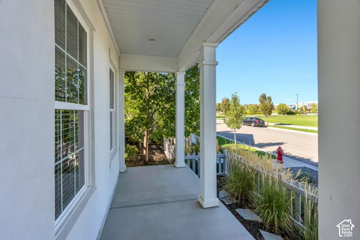 Covered front porch with white columns, stucco exterior, and concrete flooring