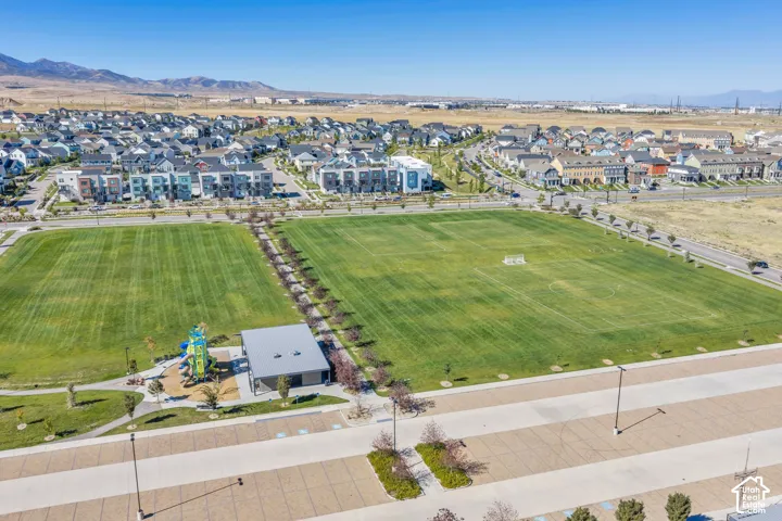 Expansive recreational park featuring two large grassy fields, a dedicated playground area, and a modern covered structure