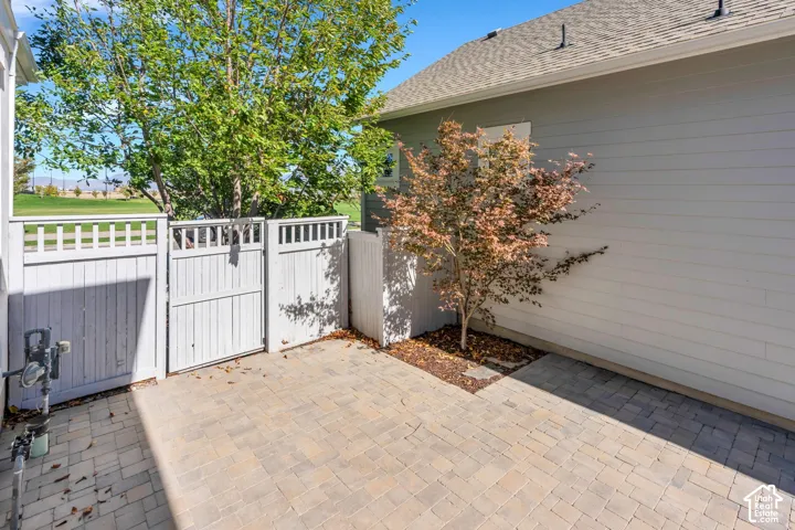 Paved patio area with a white privacy fence and gate