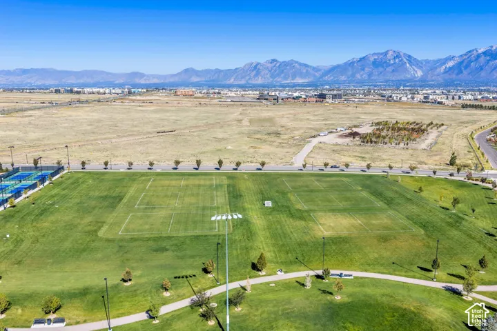 Expansive green space featuring athletic fields, paved walking paths, multiple tennis courts, and distant mountain scenery